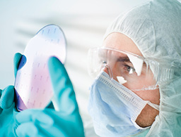 Engineer in cleanroom looking at semiconductor wafer